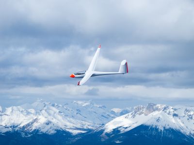 Glider in the air in front of snowy mountains